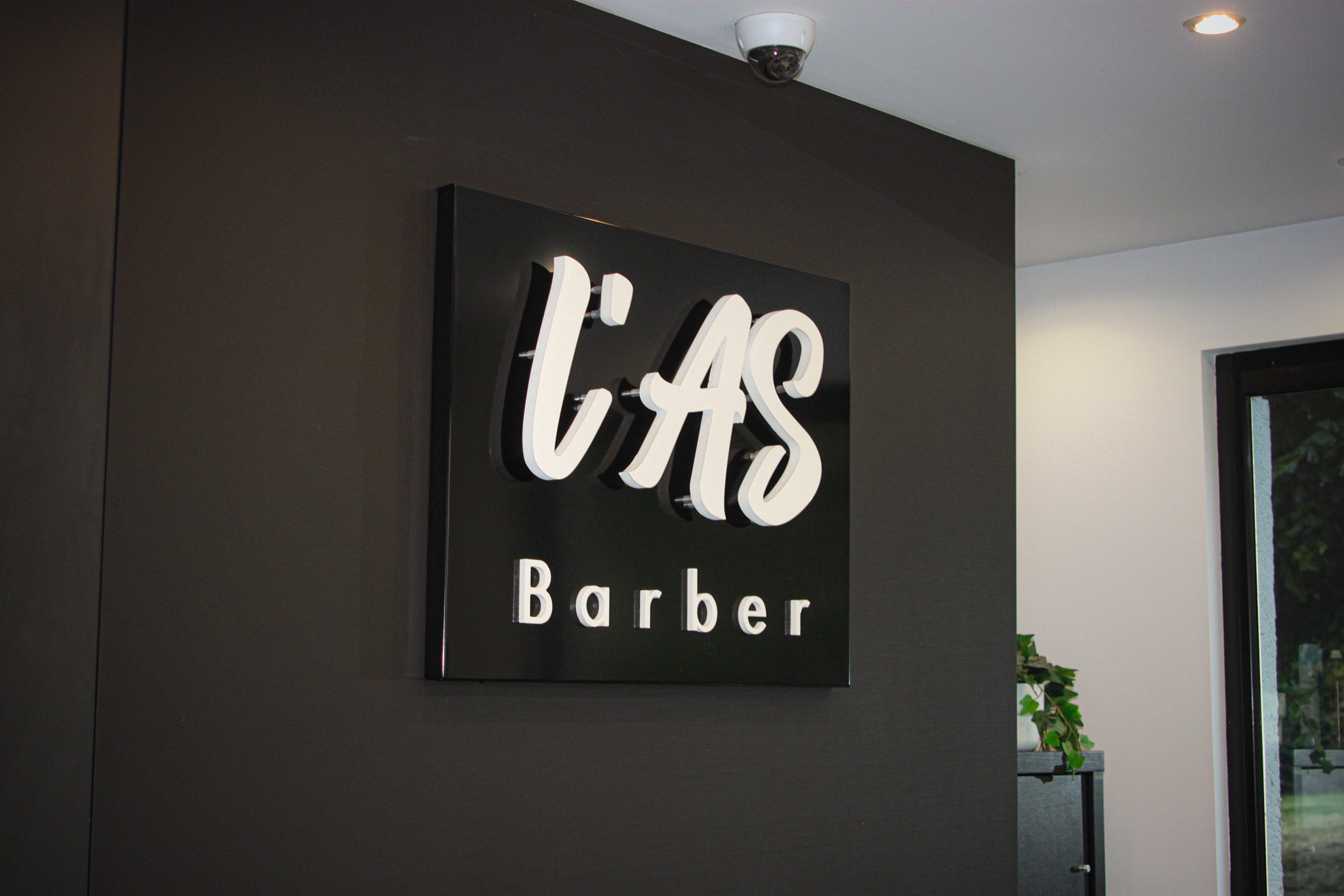 Enseigne L'AS Barber a l'interieur du salon
